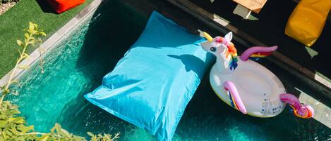 A swimming pool with a blue inflatable pillow and a unicorn float.