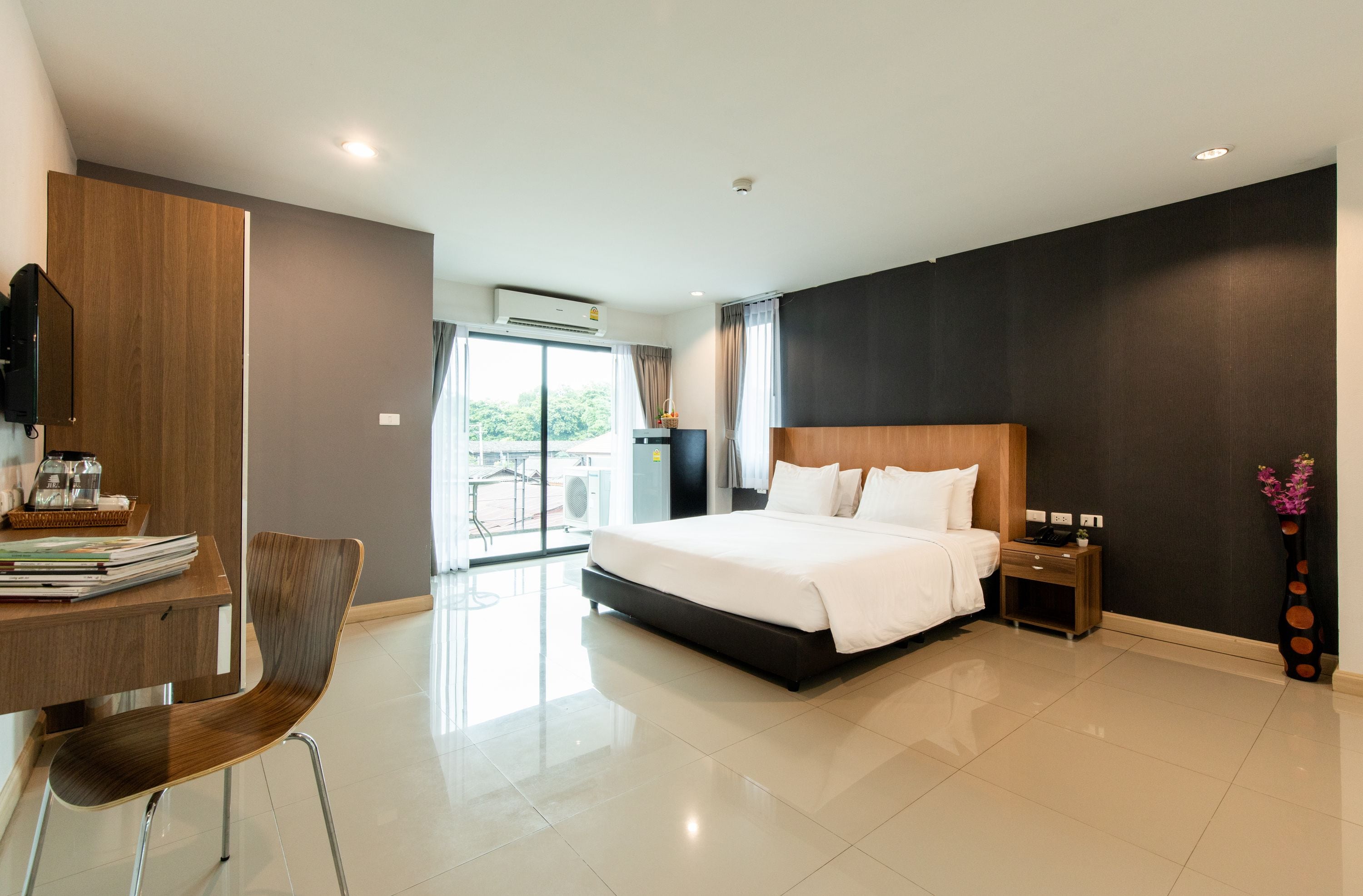 Une chambre d’hôtel moderne dotée d’un grand lit, d’un bureau avec une chaise, d’une télévision et offrant une vue sur l’extérieur.