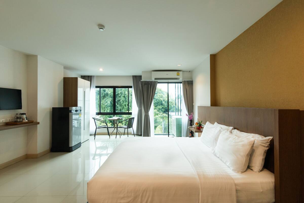 Een hotelkamer met een groot bed, een televisie, een bureau en een raam met gordijnen.