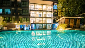 A swimming pool with a tiled floor, surrounded by a building with multiple windows and balconies. - Jira Boutique Residence (Chiang Mai)
