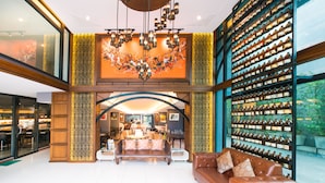 A spacious lobby with a central seating area, a large chandelier, and a wine display wall. - Jira Boutique Residence (Chiang Mai)