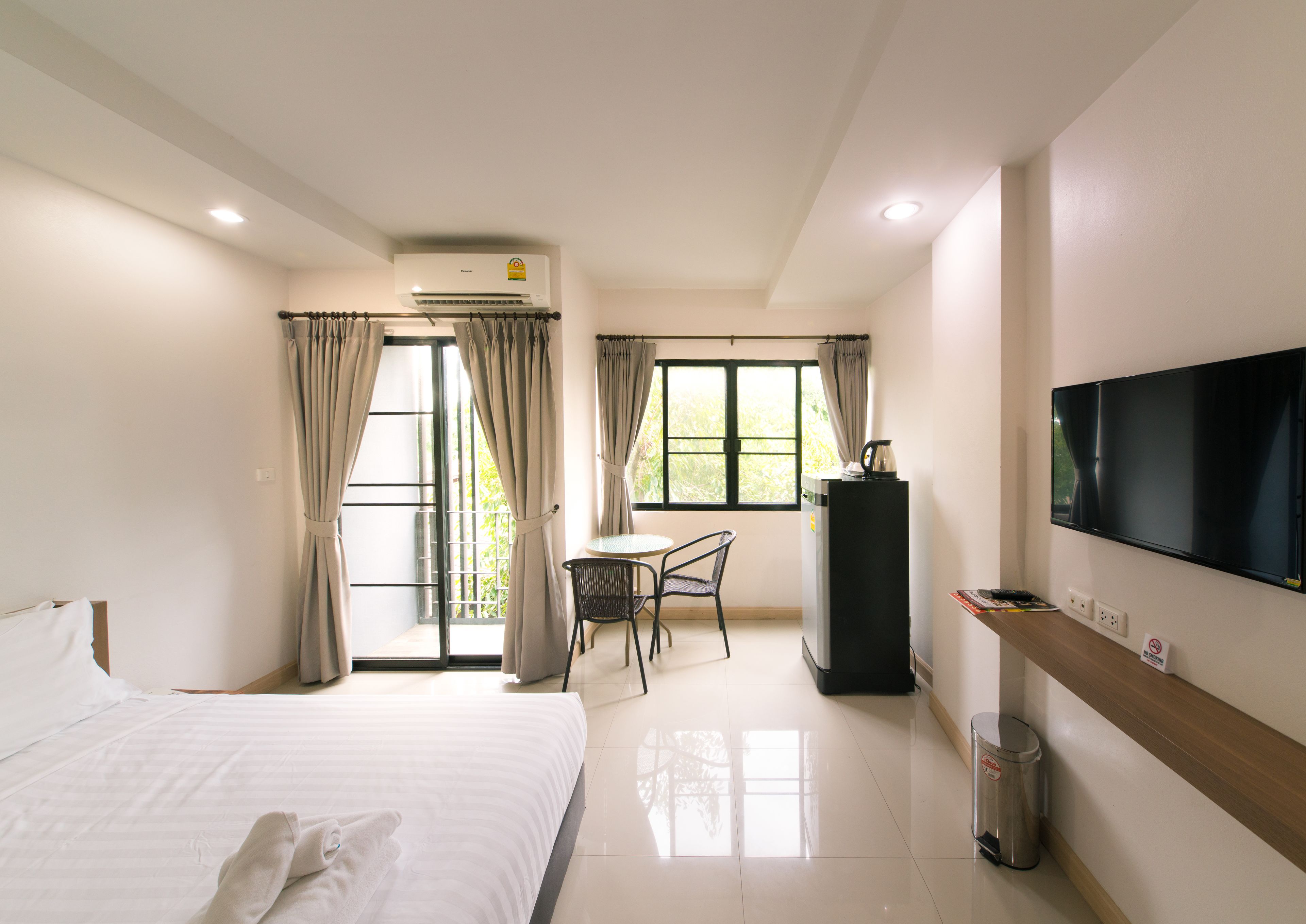 A hotel room with a bed, a desk, a television, and a window with curtains.