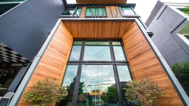 A modern building with large glass windows, wooden paneling, and two potted plants. - Jira Boutique Residence (Chiang Mai)