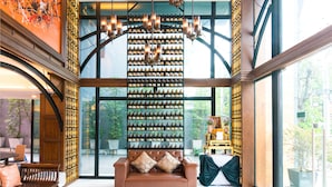 A spacious room with a large window, a brown leather sofa, and a wall of wine bottles. - Jira Boutique Residence (Chiang Mai)