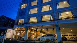 A hotel with a modern facade, multiple windows, and a car parked in the driveway. - The Pawin (Chiang Mai)