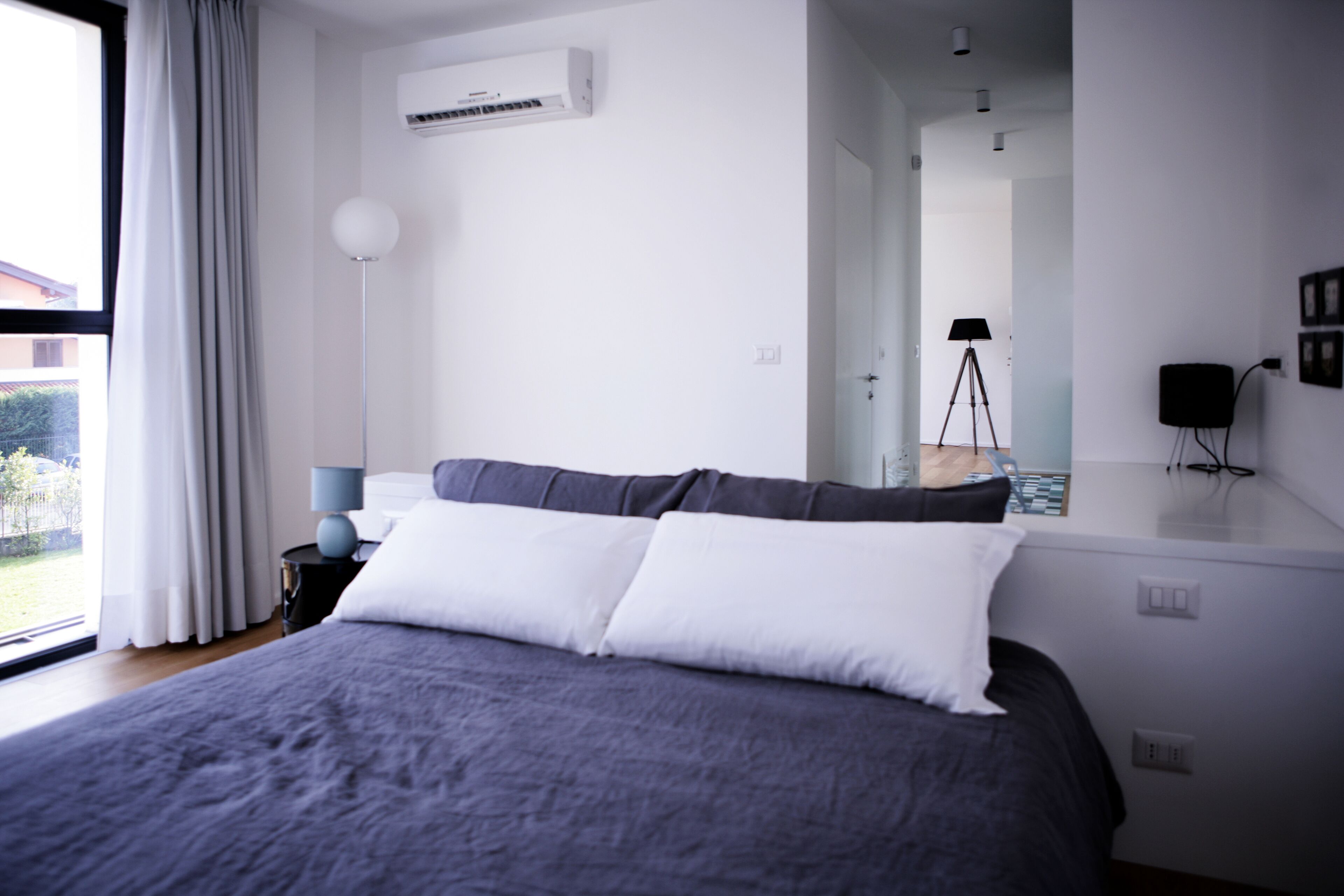 Une chambre à coucher moderne avec un grand lit, une lampe sur pied et une vue par la fenêtre.