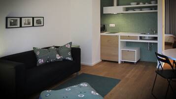 A compact living space with a sofa, a small dining table, and a kitchenette.