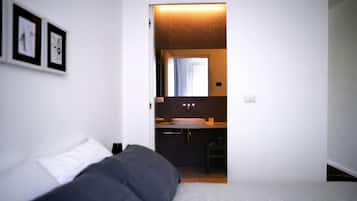 Une chambre avec un lit, une salle de bain avec un lavabo et un miroir, et des tableaux encadrés accrochés au mur.