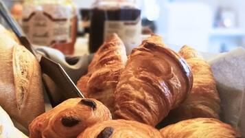 Variedad de panes y pasteles, incluyendo baguettes y croissants, expuestos en una panadería.
