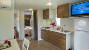 Una cocina moderna con estufa integrada, un fregadero y un refrigerador. Hay un televisor montado sobre la estufa que muestra una guía de configuración de televisión.