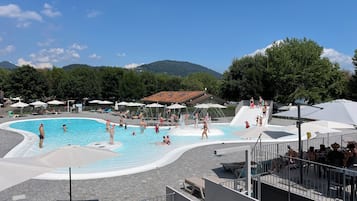Un espace piscine doté d’un toboggan et de chaises longues.