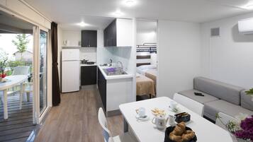 Un espacio habitable compacto con kitchenette, comedor y sofá.