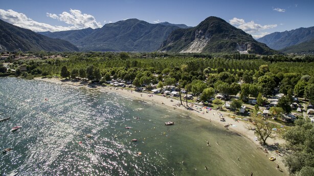 Una zona costera con playa, lago y montañas al fondo.