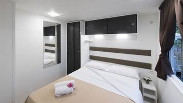 A modern bedroom with a bed, a bedside table, a mirror, and a window with curtains.