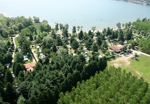 Luchtbeeld van een camping met campers, een strand en een meer met boten.