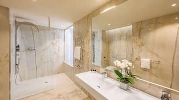 Un bagno moderno con un grande specchio, due lavabi, una doccia e pareti in marmo.