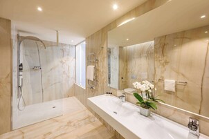 Un bagno moderno con un grande specchio, due lavabi, una doccia e pareti in marmo.