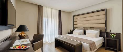 Habitación de hotel con cama, mesitas de noche, escritorio con lámpara, una silla y televisión.