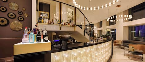 A modern bar area with a curved counter, various liquor bottles, and a staircase leading to an upper level.