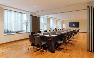 A conference room with a long table, chairs, and a projector screen.