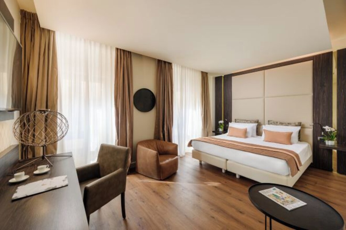 Una habitación de hotel con cama, escritorio, silla y una mesita.