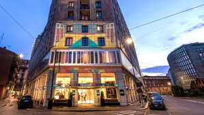 Un edificio alto con fachada colorida, múltiples ventanas y una entrada a nivel de calle con una tienda llamada "The Square".