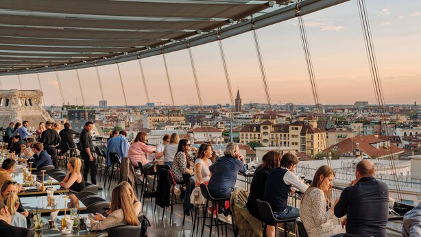 Un restaurante en la azotea con mesas al aire libre y vistas a la ciudad.