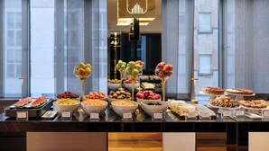 Un bufé con diversas frutas, pasteles y postres.