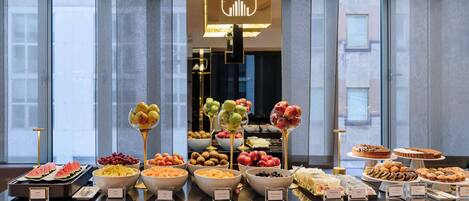A buffet with various fruits, pastries, and desserts.