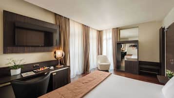 Hotelkamer met een bed, bureau met flatscreen televisie, stoel, nachtkastje met lamp en een grote spiegel.