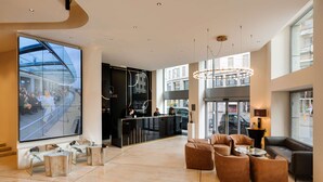 Un moderno vestíbulo de hotel con mostrador de recepción, zona de estar y ventanas amplias con vistas a la ciudad.