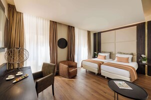 Una camera d'albergo con un letto, due sedie, un tavolino e un tavolo rotondo con una rivista.