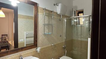 A bathroom with a sink, bidet, toilet, and a glass-enclosed shower.