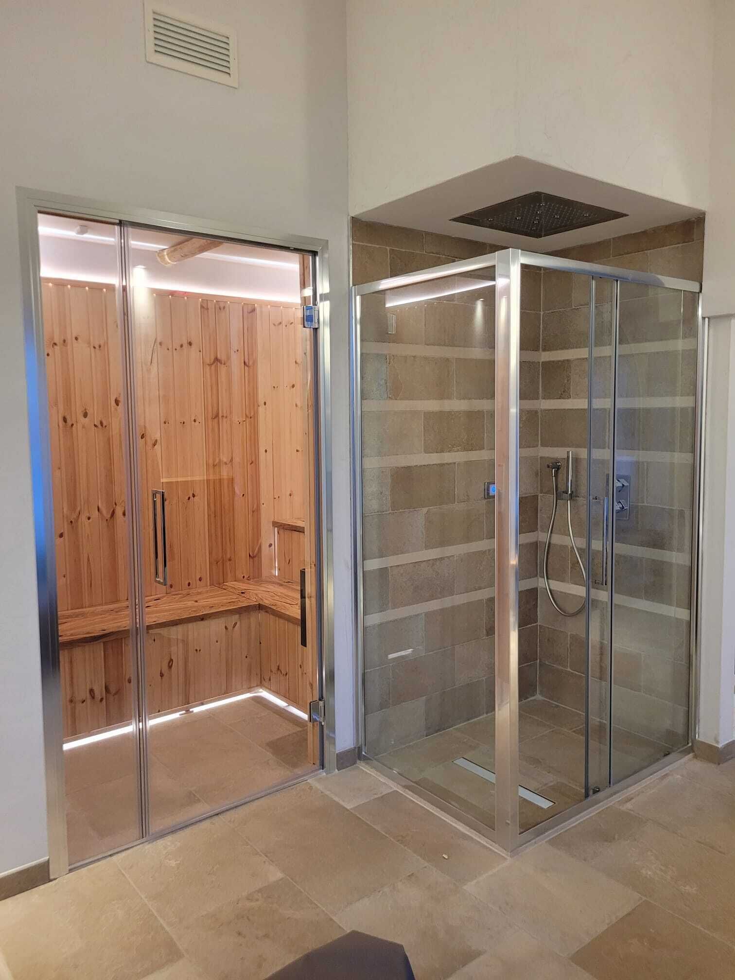 A modern bathroom with a glass-enclosed shower, a wooden sauna, and a tiled floor.