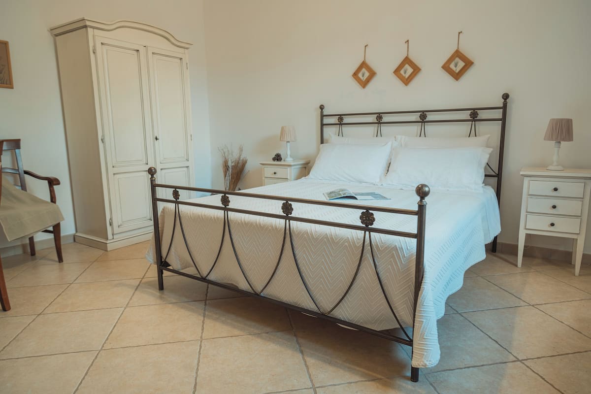 Ein Schlafzimmer mit Bett, Nachttischen, einem Kleiderschrank und einem Sessel.
