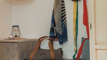 A room with a wooden bench, a wall-mounted shelf with a candle, a drum, and a bag on the bench.