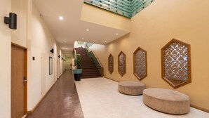 A spacious hallway with a wooden floor, a staircase, and a seating area with ottomans. - Rimkhobfa Urban Resort (Samut Prakan)