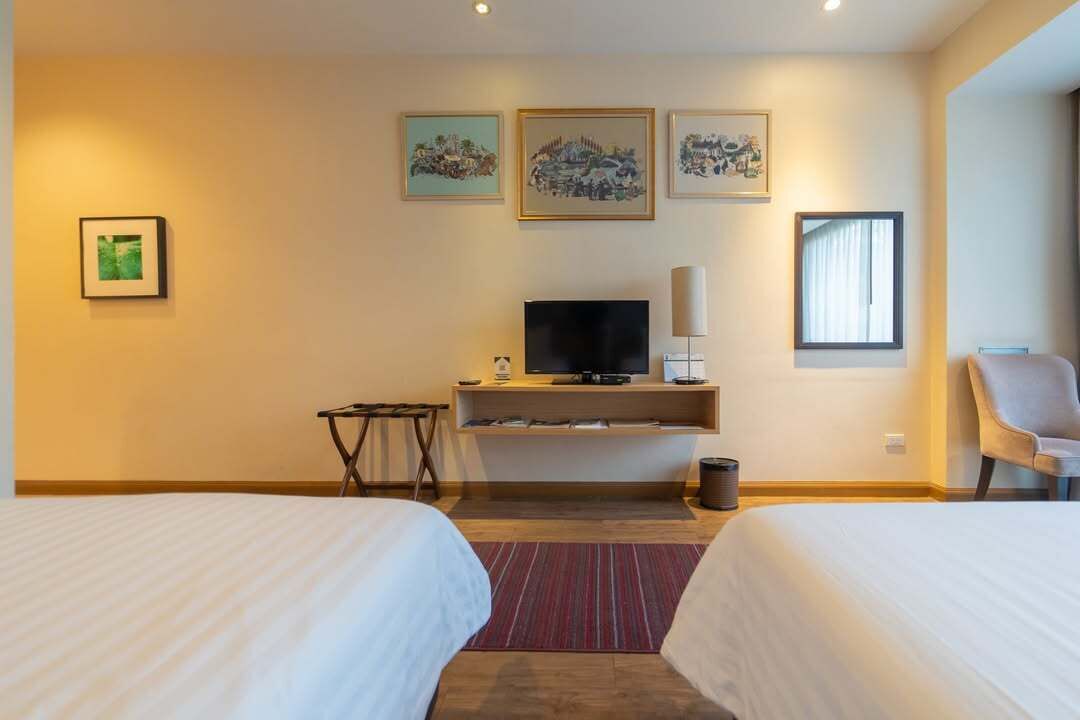 Une chambre d’hôtel avec deux lits, une télévision, un bureau et des œuvres d’art accrochées au mur.