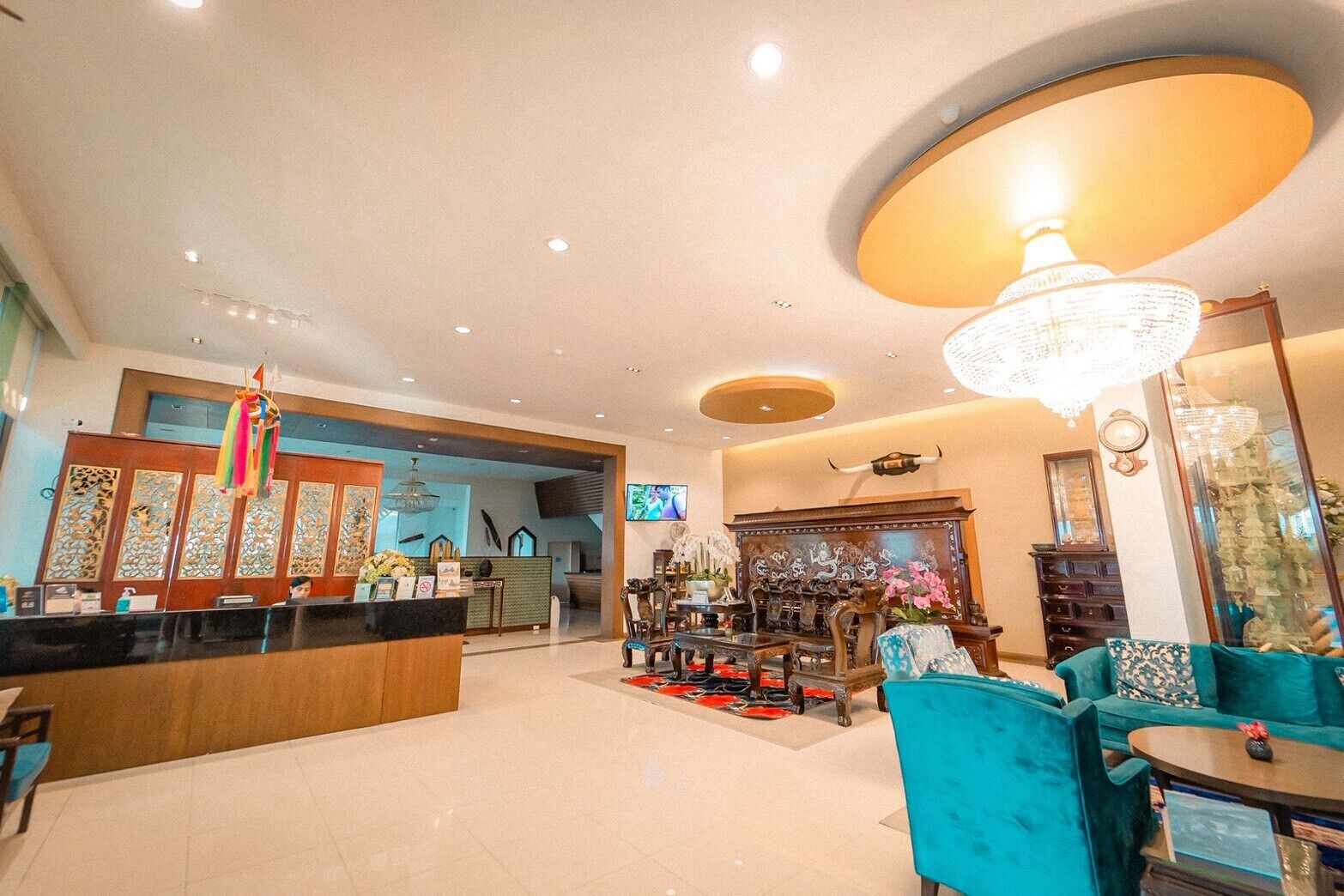 A hotel lobby with a reception desk, seating area, and a chandelier.