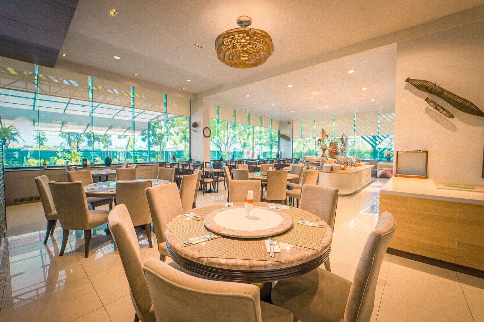A modern dining area with round tables, chairs, and a central decorative light fixture.