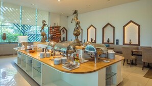 A breakfast buffet area with a curved counter, various food items, and decorative horse statues. - Rimkhobfa Urban Resort (Samut Prakan)