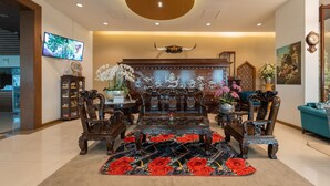 A traditional-style living room with ornate furniture, a large floral rug, and a television mounted on the wall. - Rimkhobfa Urban Resort (Samut Prakan)
