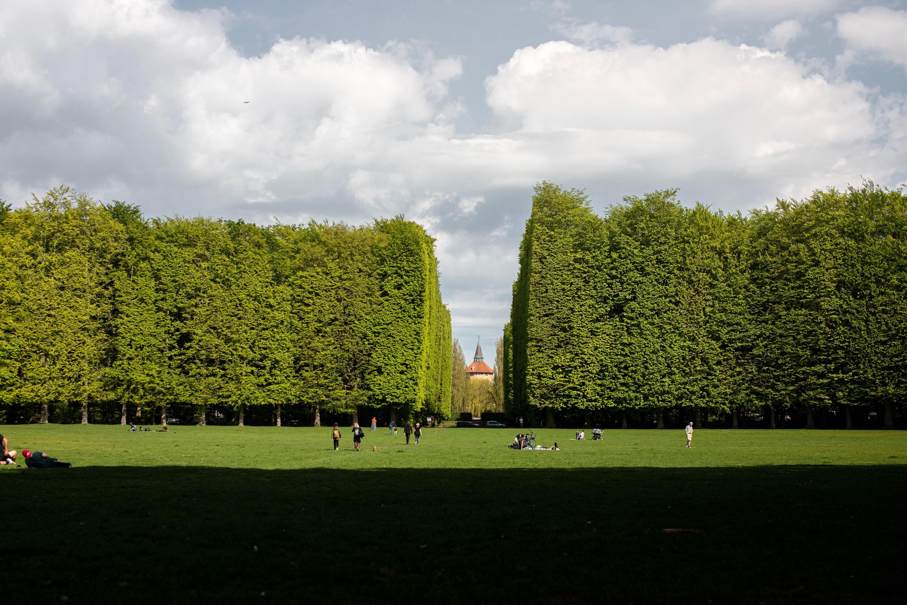 A park with a central building, surrounded by neatly trimmed hedges.