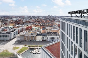 Un hotel de gran altura con vistas a un paisaje urbano que incluye un río y varios edificios.