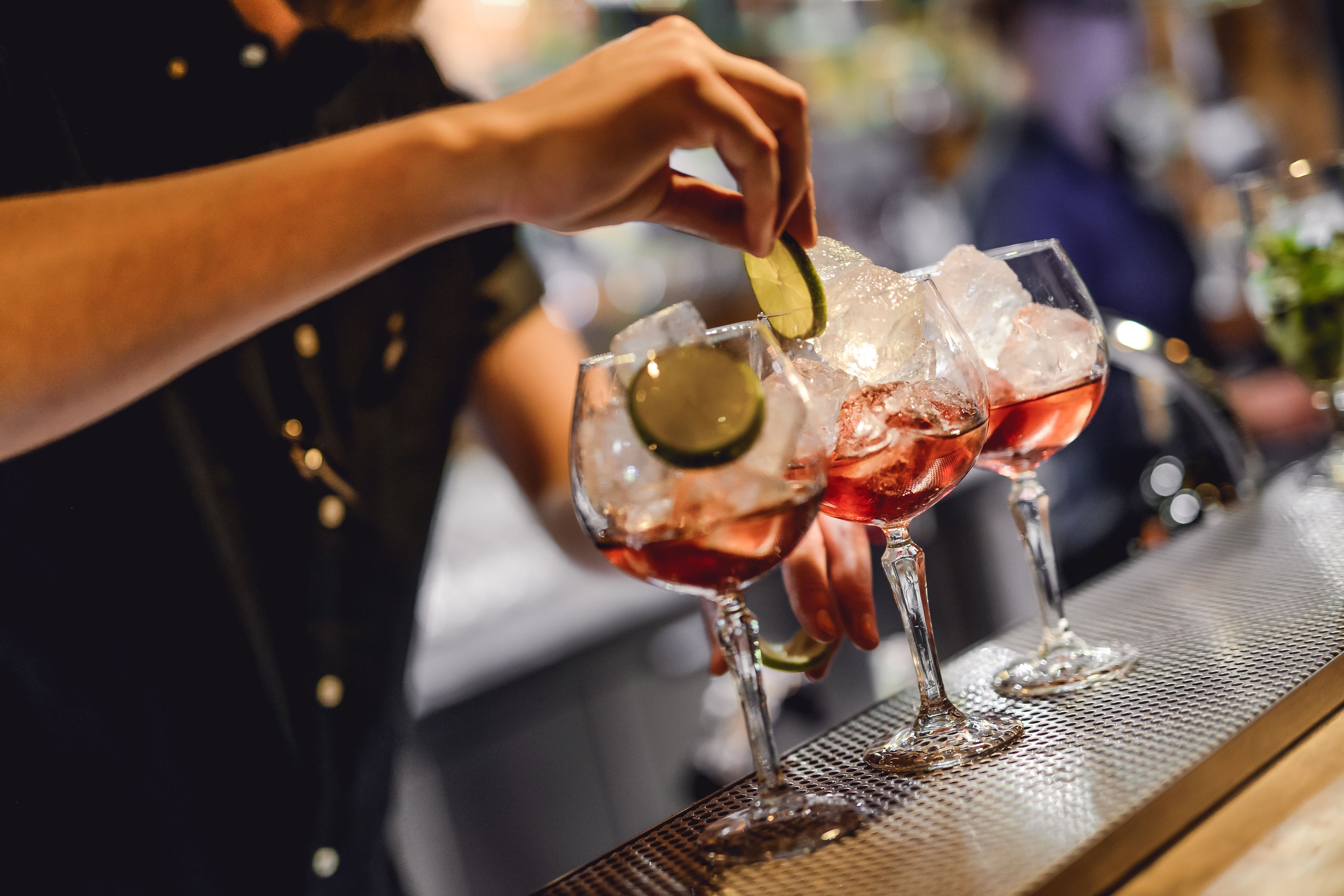 A bartender preparing a drink with ice and a lime wedge.