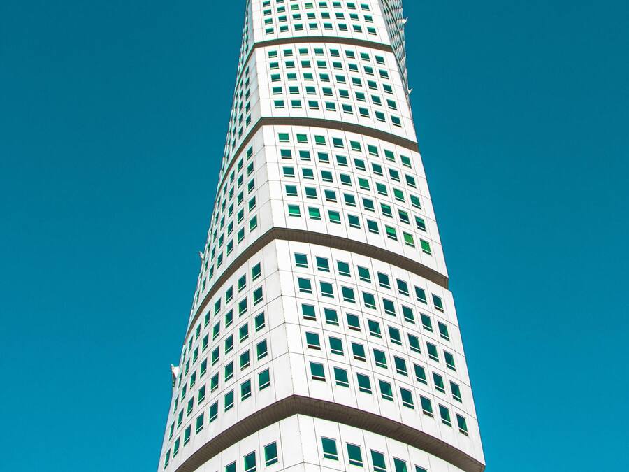 Un edificio alto y espiral con una cuadrícula de ventanas contra un cielo azul despejado.