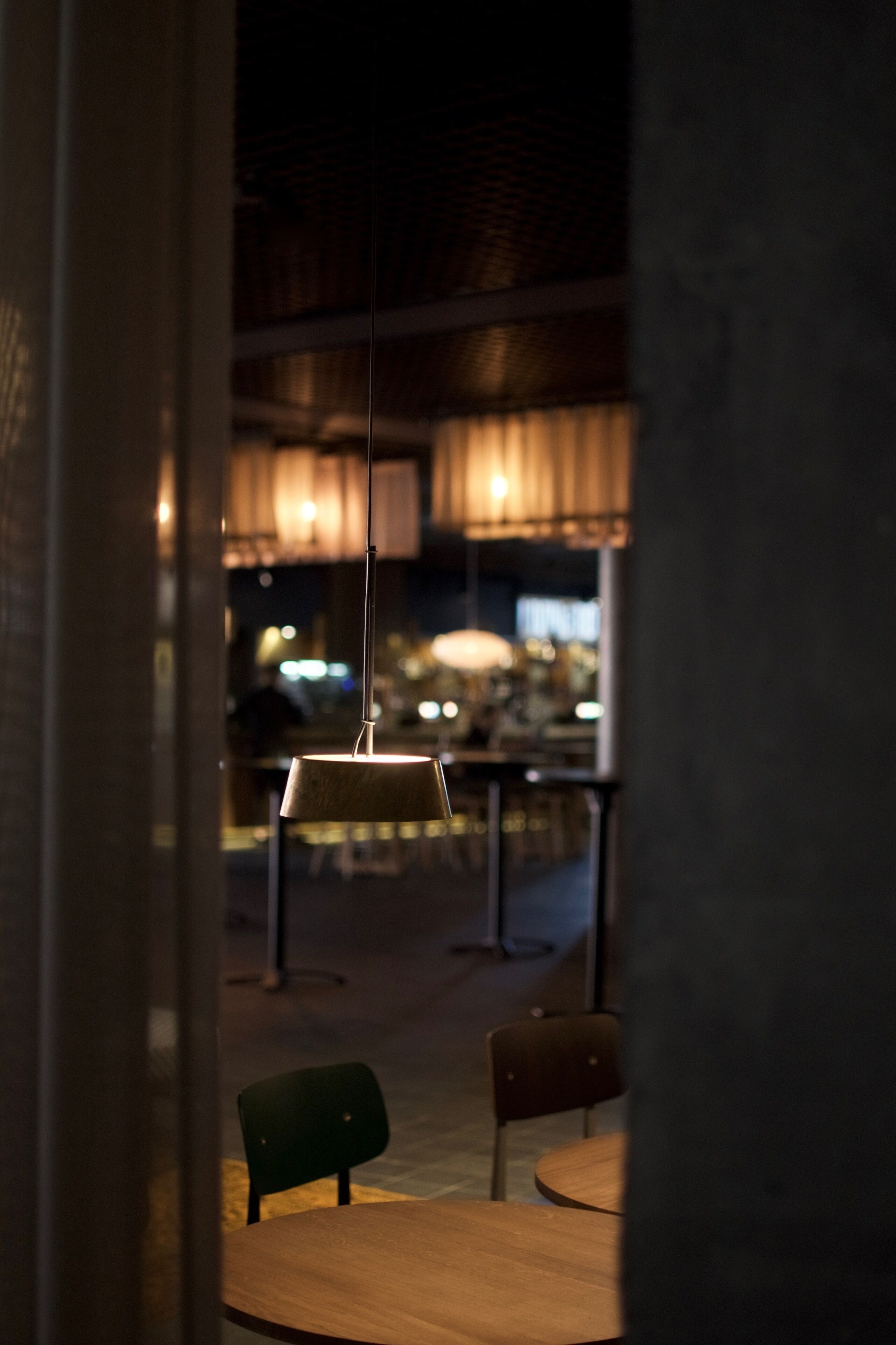 An interior view of a restaurant with a wooden table, chairs, and hanging pendant lights.