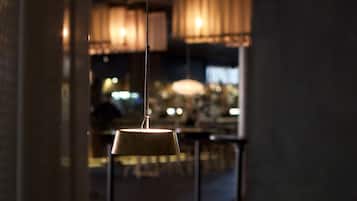 An interior view of a restaurant with a wooden table, chairs, and hanging pendant lights.