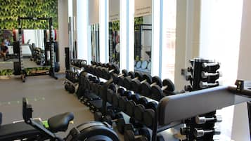 Une salle de sport équipée de divers appareils de musculation, notamment des haltères et des barres.