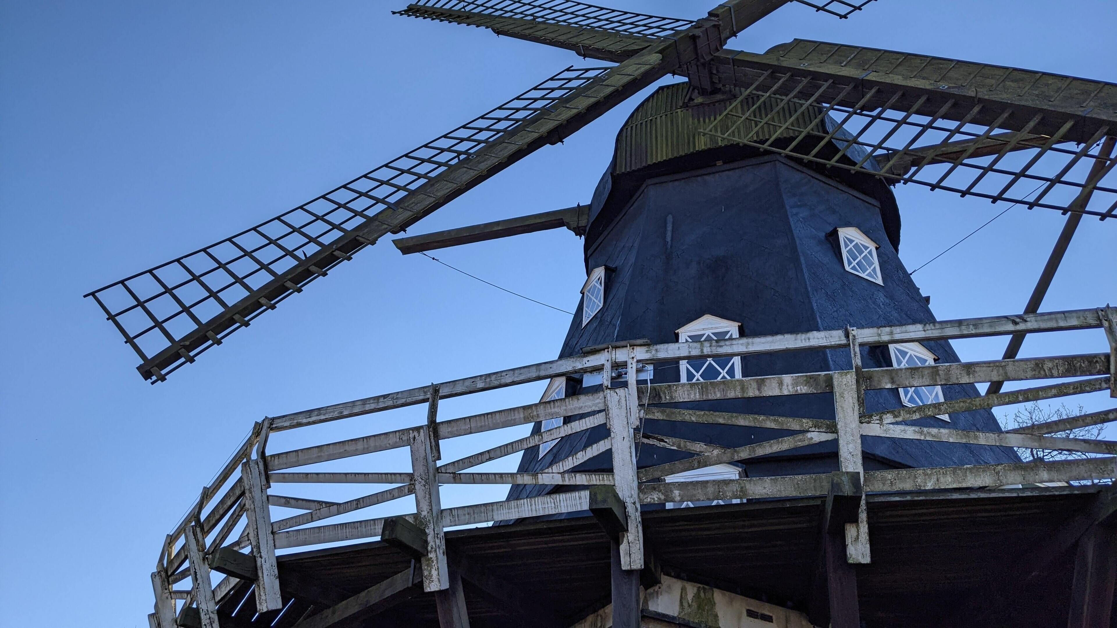 Un molino de viento con estructura de celosía metálica y cuerpo azul oscuro.